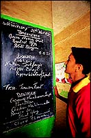 A student studying the lunch menu for the day put up on a blackboard.